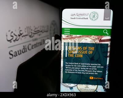 Persona che detiene un cellulare con pagina web dell'istituto finanziario Banca centrale saudita (SAMA) davanti al logo. Messa a fuoco al centro del display del telefono. Foto Stock