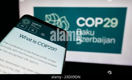 Telefono cellulare con sito web della Conferenza delle Nazioni Unite sui cambiamenti climatici 2024 COP29 davanti al logo. Mettere a fuoco in alto a sinistra sul display del telefono. Foto Stock