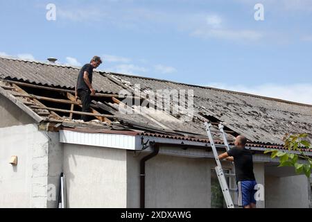 Non esclusiva: VASYLKIV, UCRAINA - 23 GIUGNO 2024 - due uomini riparano il tetto di una casa danneggiata da un attacco missilistico russo, Vasylkiv, regione di Kiev, nort Foto Stock