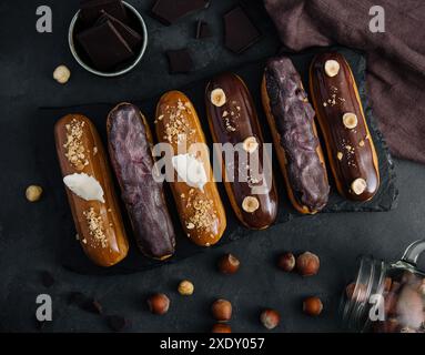 Dolci eclari di cioccolato su tavola di legno nera Foto Stock