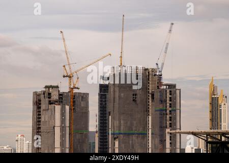 Vista in timelapse delle grandi gru da costruzione che lavorano in cima a grattacieli a Bangkok, Thailandia, con nuvole mobili e grattacieli in ba Foto Stock