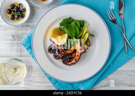 Polpo grigliato con rucola e mini verdure su un piatto di porcellana bianca Foto Stock