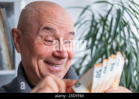 uomo soddisfatto che detiene euro, denaro in euro, conti bollette, gioisce del successo, anticipa su cosa spenderlo, incoraggiando un buon comportamento finanziario, ce Foto Stock
