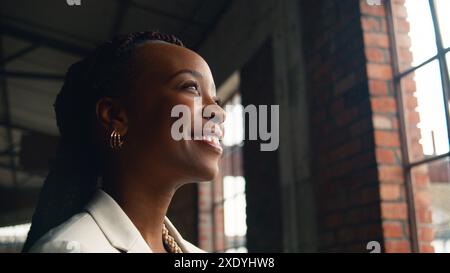 Ritratto di una donna sorridente in un moderno ambiente industriale con luce naturale Foto Stock