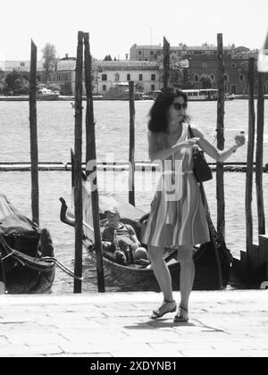 Venezia, Italia - 30 giugno 20220 donna che scatta un selfie con il suo smartphone mentre si allontana da un gondoliere in attesa di clienti a venezia, italia Foto Stock