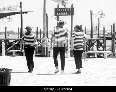 Venezia, Italia - 30 giugno 20220 tre gondolieri si allontanano dalla macchina fotografica in una giornata di sole a venezia Foto Stock