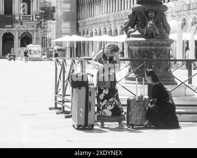 Venezia, Italia - 30 giugno 20220 due donne turisti stanno controllando i loro bagagli in una piazza deserta a venezia, italia Foto Stock