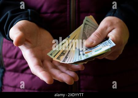 Il maschio bianco mostra le fatture del dollaro nella sua vista anteriore del primo piano della mano Foto Stock