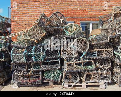 Vasi di aragosta utilizzati nella pesca tradizionale per i crostacei impilati contro un edificio nel porto di scarborough Foto Stock