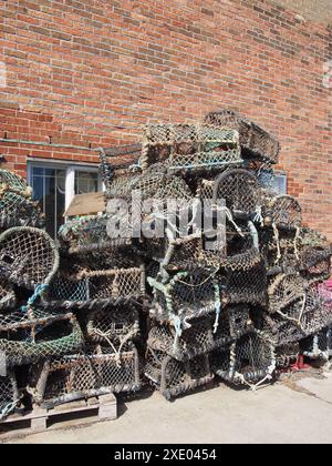 Vasi di aragosta utilizzati nella pesca tradizionale per i crostacei impilati contro un edificio nel porto di scarborough Foto Stock