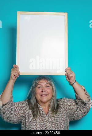 Donna più vecchia dai capelli bianchi che tiene una lavagna bianca per incollare il testo sopra Foto Stock