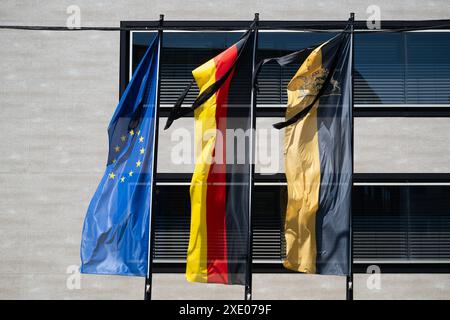 25 giugno 2024, Baden-Württemberg, Stoccarda: Le bandiere di lutto possono essere viste sulle bandiere d'Europa (l-r), Germania e Baden-Württemberg di fronte al Ministero degli interni del Baden-Württemberg. Il 24.06.2024, un ufficiale di polizia con lo squadrone motociclistico della polizia stradale di Stoccarda scortò il capo del governo ungherese V. Orban come ospite di stato. Durante il viaggio verso l'aeroporto, una donna si è scontrata con la moto dell'agente nella sua auto, come segnalato dalla polizia e dall'ufficio del pubblico ministero. L'agente di polizia è morto e un collega è rimasto gravemente ferito. Foto: Marijan Murat/dpa Foto Stock