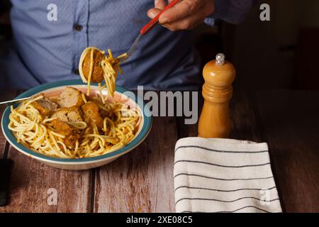 Uomo che mangia polpette con spaghetti Foto Stock