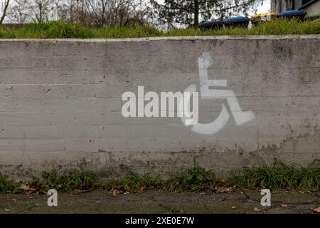 Simbolo di una sedia a rotelle con spazio di parcheggio su una parete Foto Stock