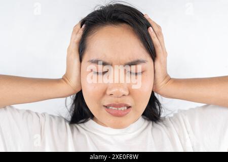 Una donna con la testa abbassata e le mani sulle orecchie. Sembra che stia soffrendo Foto Stock