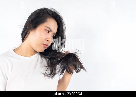Una donna con i capelli lunghi sta guardando la macchina fotografica. Si è appena tagliata i capelli e li sta tenendo. Giovane donna triste che tiene i suoi lunghi capelli divisi finisce in h Foto Stock