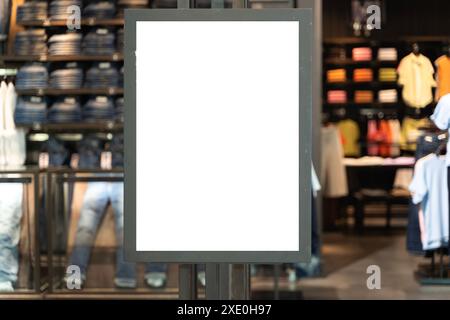 Cartello bianco verticale sulla parte anteriore di un negozio di abbigliamento con una finestra di vetro. Negozio di abbigliamento firmato nel centro commerciale. Foto Stock