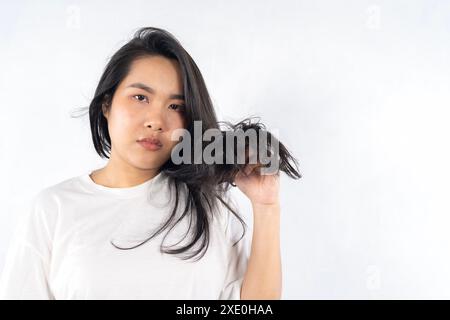Giovane donna nera con capelli disordinati su sfondo bianco. Le donne asiatiche sono preoccupate per i loro capelli danneggiati che causano una mancanza di fiducia. Trattamento di perdita di capelli Foto Stock