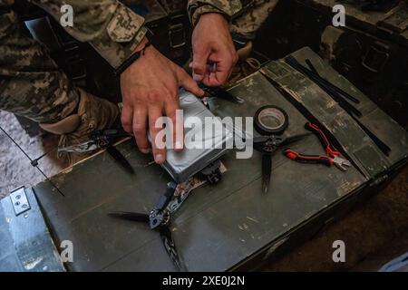 Un soldato ucraino della 92a brigata, noto come la Brigata "Achille", lega esplosivi a un drone FPV in una posizione a circa 10 chilometri dal confine russo nell'Oblast di Charkiv, Ucraina, il 12 giugno 2024. I droni First Person View (FPV) hanno cambiato la natura della guerra in Ucraina, con le forze ucraine e russe che si affidano a questi droni, armati di esplosivi e controllati da remoto da un pilota che indossa una cuffia. (Foto di Laurel Chor / SOPA Images/Sipa USA) Foto Stock