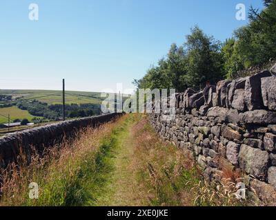 Stretta strada di campagna che scende da una collina nella panoramica campagna dello yorkshire occidentale vicino al villaggio di colden a calderdale, nello yorkshire occidentale Foto Stock