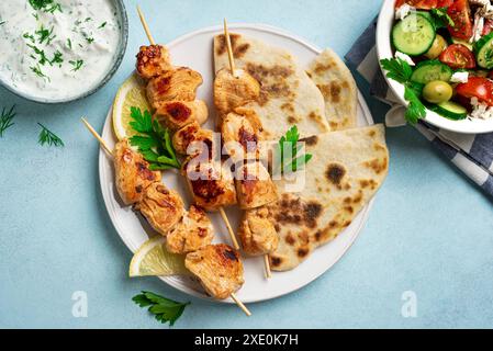 Kebab di souvlaki di pollo, insalata greca di verdure e focaccia pita. Pasto sano mediterraneo - spiedini di carne e insalata, salsa tzadziki, keto equilibrato Foto Stock