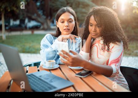 Smartphone con vista da due donne in un caffè all'aperto Foto Stock