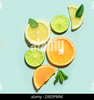 Composizione estiva di fette di agrumi e foglie di menta su sfondo verde pastello, vista dall'alto. Layout creativo di foglie di arancia, limone, lime e menta Foto Stock