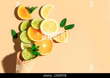 Idea minimalista con cono per cialde gelato e fette di agrumi freschi: Arancia, lime, limone su sfondo arancione. Concetto di frutta e cibo estivo minimalista Foto Stock