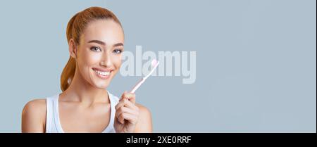 Donna sorridente con lo spazzolino in mano, striscione Web Foto Stock