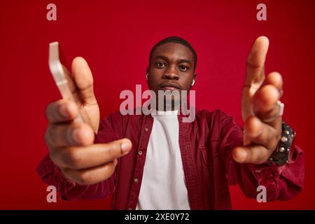 Uomo emotivo di aspetto africano con un telefono in mano, tecnologia di comunicazione, gioia e successo Foto Stock