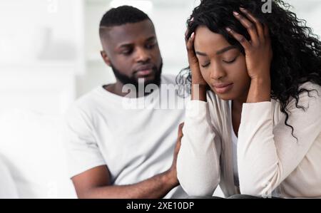 Uomo che conforta una donna sconvolta al chiuso Foto Stock