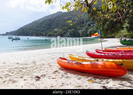 Kayak di plastica rossi giacevano sulla costa. Spiaggia estiva con bandiera delle Seychelles in una giornata di sole Foto Stock