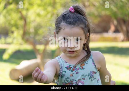 Bambina dotata di potere e sicura di sé, guarda la fotocamera con un sorriso radioso in una giornata calda. Perfetto per catturare sicurezza, gioia e pos Foto Stock