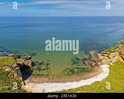 Costa di Hopeman Moray Firth, piccola insenatura e spiaggia in Scozia con scogliere di arenaria dorata e mare verde blu Foto Stock