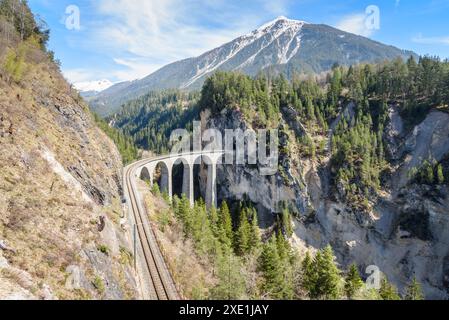 Vidotto ferroviario curvilineo monobinario nelle Alpi svizzere in una giornata di sole primaverili Foto Stock