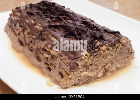 Primo piano di una decadente torta al cioccolato. Una fetta mancante rivela l'interno umido e stratificato, evidenziando il delizioso testo del biscotto Foto Stock