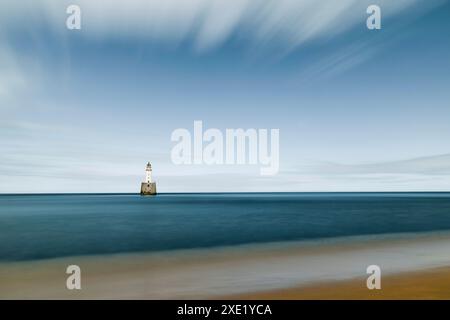 Il faro di Rattray Head si erge a sentinella sulle insidiose rive sabbiose di Rattray Head, dove i resti scheletrici di relitti di legno fungono da nave Foto Stock