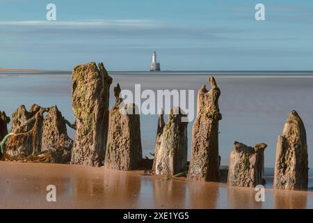 Il faro di Rattray Head si erge a sentinella sulle insidiose rive sabbiose di Rattray Head, dove i resti scheletrici di relitti di legno fungono da nave Foto Stock