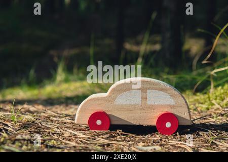 Macchinina giocattolo in legno su sfondo verde della foresta. Eco-car Concept World auto giorno libero veicolo elettrico ambiente auto transpo Foto Stock