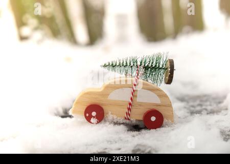 Macchina di legno che trasporta l'albero di Natale sulla neve. Spazio per copiare il testo Toy car in un paesaggio innevato. Buon Natale e felice anno nuovo Foto Stock