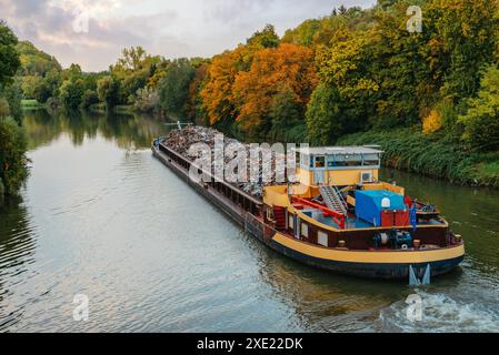 Settore dei trasporti. La chiatta della nave trasporta rottami metallici e sabbia con ghiaia. La chiatta caricata con rottami metallici si trova sulla strada Foto Stock