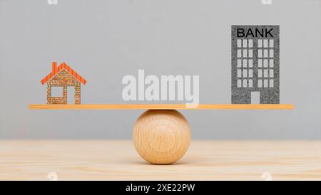 Baufinanzierung Auf einer Wippe ist ein Modellhaus und die Symbolische Finanzierung im Gleichgewicht - FOTOMONTAGE **** costruzione finanziamento Di Un modello Foto Stock