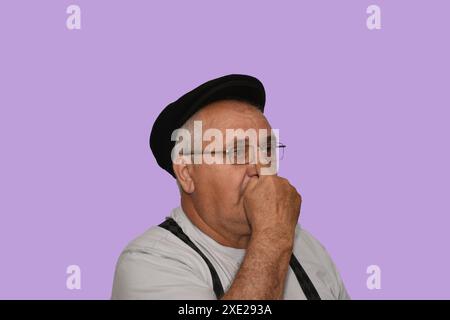 Ritratto di un uomo anziano con gli occhiali e un cappello, che regola gli occhiali con il dito. Foto Stock
