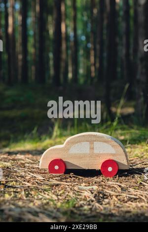 Macchinina giocattolo in legno su sfondo verde della foresta. Eco-car Concept World auto giorno libero veicolo elettrico ambiente auto transpo Foto Stock