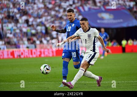 Colonia, Germania. 25 giugno 2024. Calcio, UEFA Euro 2024, Campionato europeo, Inghilterra - Slovenia, turno preliminare, gruppo C, giorno 3, stadio di Colonia, Petar Stojanovic (l) della Slovenia e Phil Foden dell'Inghilterra lottano per il pallone. Credito: Marius Becker/dpa/Alamy Live News Foto Stock