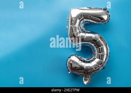 5 cinque palloncini metallici isolati su sfondo blu. Biglietto d'auguri numero palloncino in lamina d'argento concetto di festa per buon compleanno. Co Foto Stock