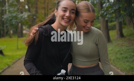 Due donne caucasiche felici e sportive ragazze sport attivo donne che abbracciano dopo un allenamento di fitness all'aperto amiche di gen z sorridenti Foto Stock