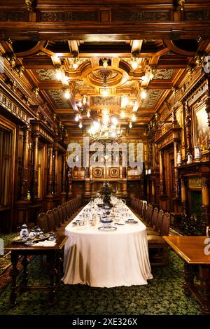 Sinaia, Romania - 26 agosto 2022: Sala da pranzo con tavolo servito ricoperto di tovaglie bianche all'interno del castello di Peles. Il ricco interno del Peles Foto Stock