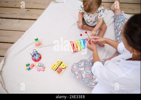 Mamma e bambino si divertono giocando con giocattoli educativi colorati su una coperta da picnic. Attività didattica e di collegamento in famiglia all'aperto. Foto Stock