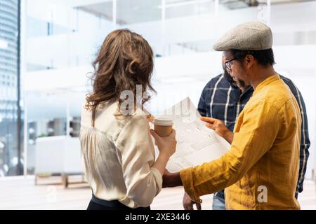 Agente immobiliare che fornisce consulenza ai clienti in merito al trasferimento e al leasing di uffici, esamina progetti dettagliati e discute del design architettonico della nuova proprietà. Negoziazione del contratto. Foto Stock